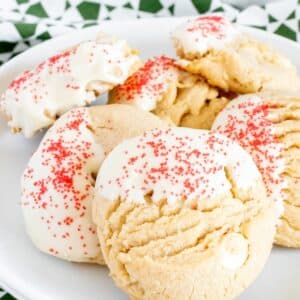 Peanut butter white chocolate chip cookies decorated with red sprinkles on a white plate.