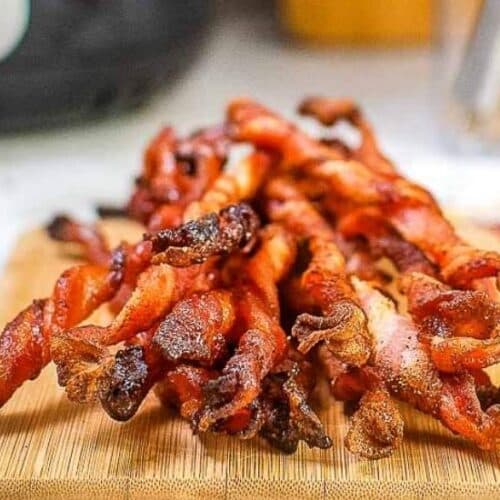 Front view of air fried twisted bacon on a wooden cutting board.