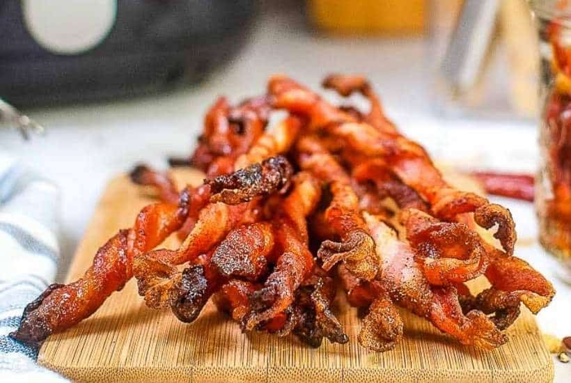 Front view of air fried twisted bacon on a wooden cutting board.