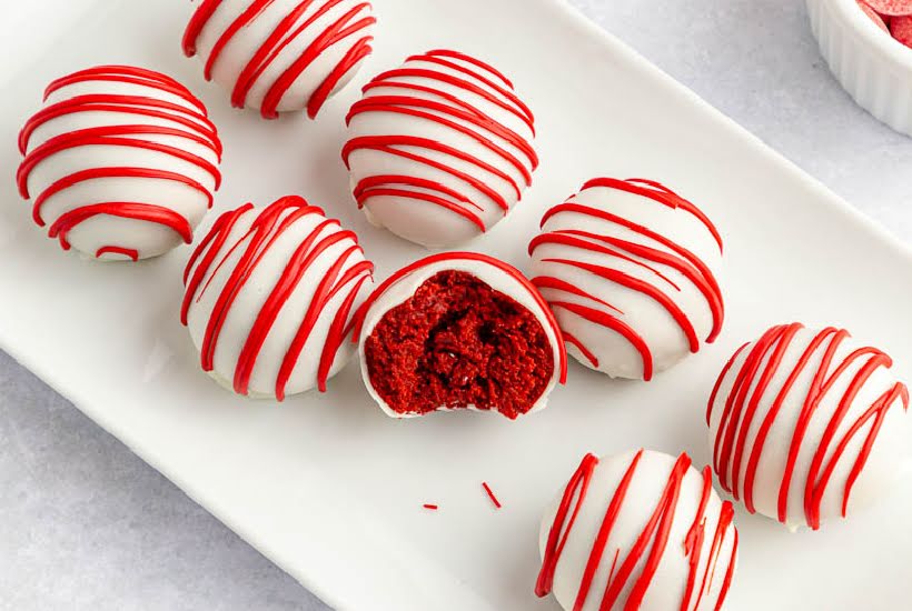 No bake red velvet cake bites on a white platter, one with a bit removed.