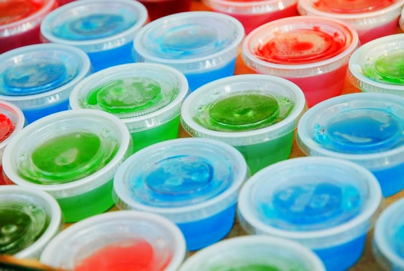 A tray of colored jello shots with lids on.