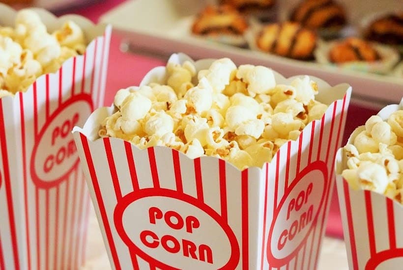 Three movie theater style boxes filled with popcorn.