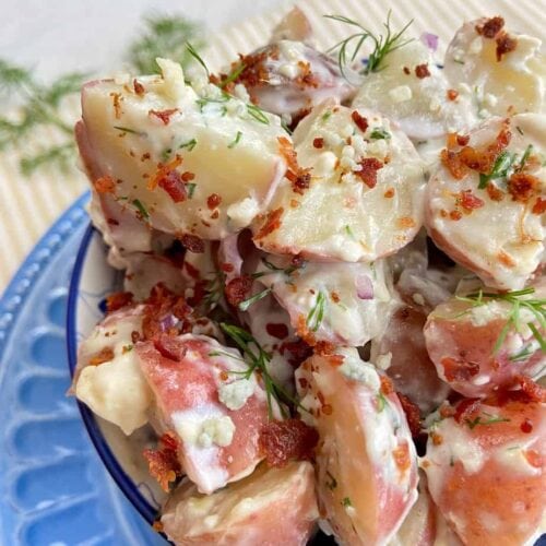 Creamy potato salad with bacon and Blue cheese dressing in a decorative serving bowl.