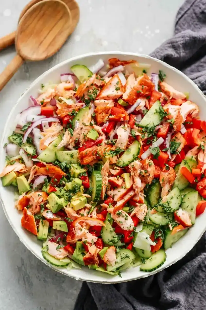 A chopped salad with salmon, peppers and onions.