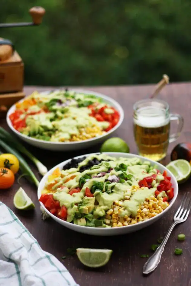 Two bowls of vegan chopped salad with corn, black beans and dressing.