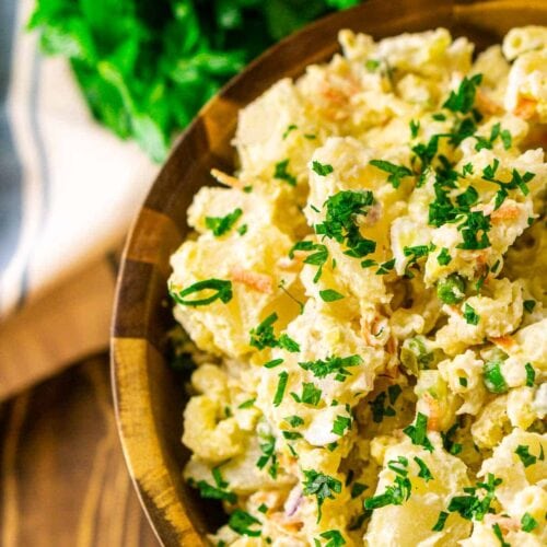 Hawaiian potato salad garnished with chopped parsley in a wood serving bowl.