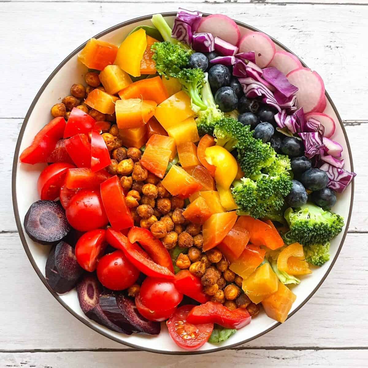 A salad in a bowl arranged in rainbow pattern.