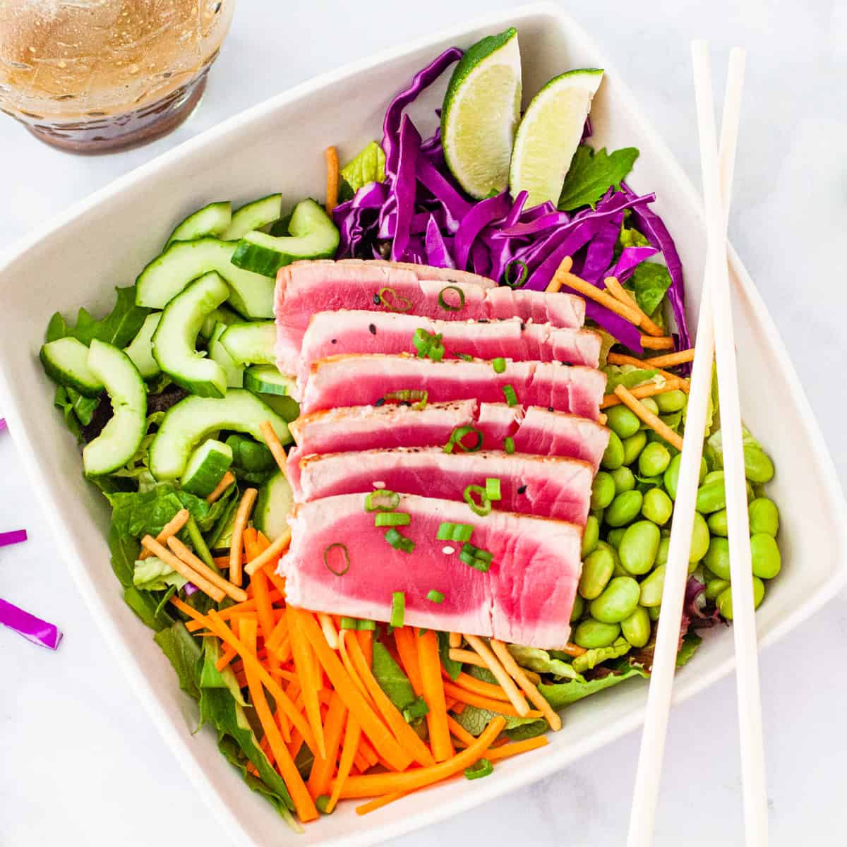 A bowl of cabbage salad with seared tuna and chopped veggies.