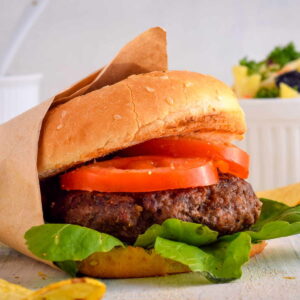 Burger made in the electric skillet and garnished with sliced tomato and lettuce.