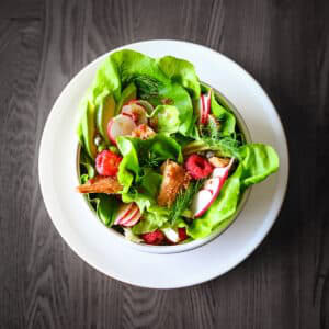 Green salad with smoked salmon, raspberries, avocado and sliced radishes.
