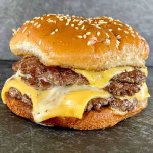 Triple smash burger with melty cheese on a Blackstone griddle.