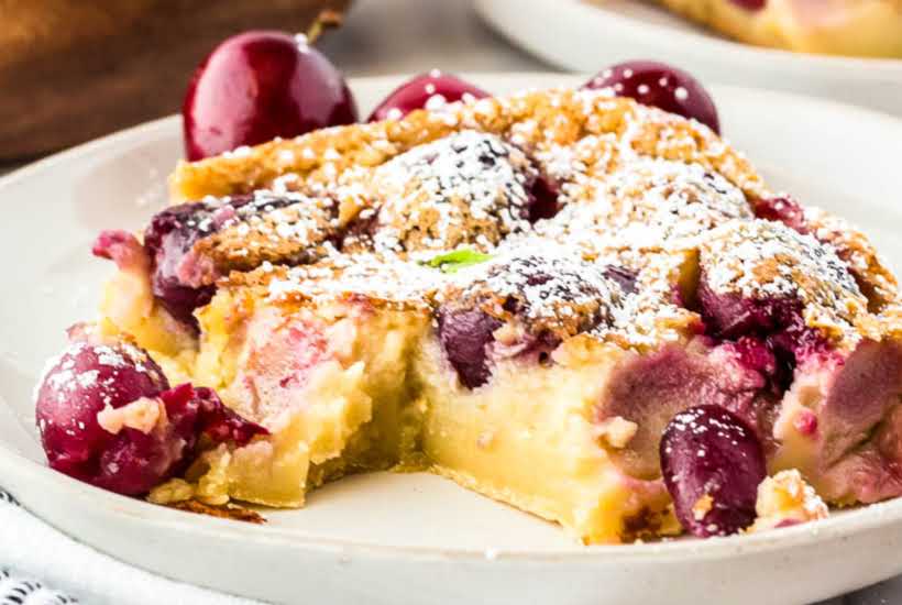 A slice of cherry clafoutis on a round white plate.