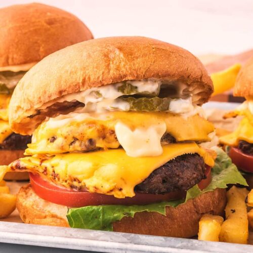 Restaurant style double smash burgers with cheese, pickles, lettuce, tomato and mayonnaise with French fries.