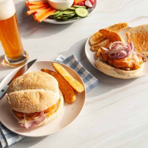 Two turkey smash burgers with potato fries on white plates.