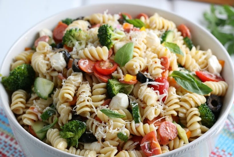 Closeup of bowl of spiral pasta salad with fresh vegetables and cheese.