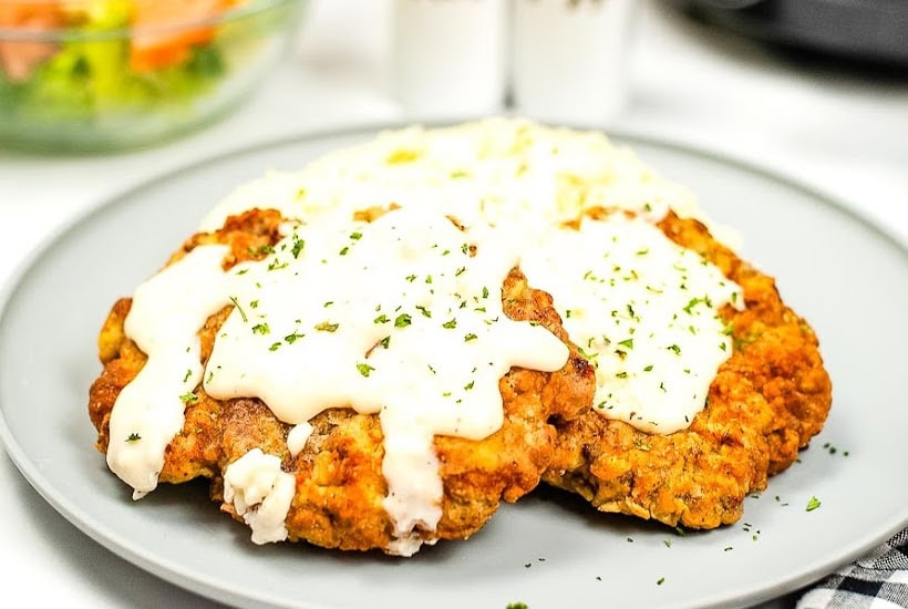 Closeup view of two chicken fried steaks covered in gravy.