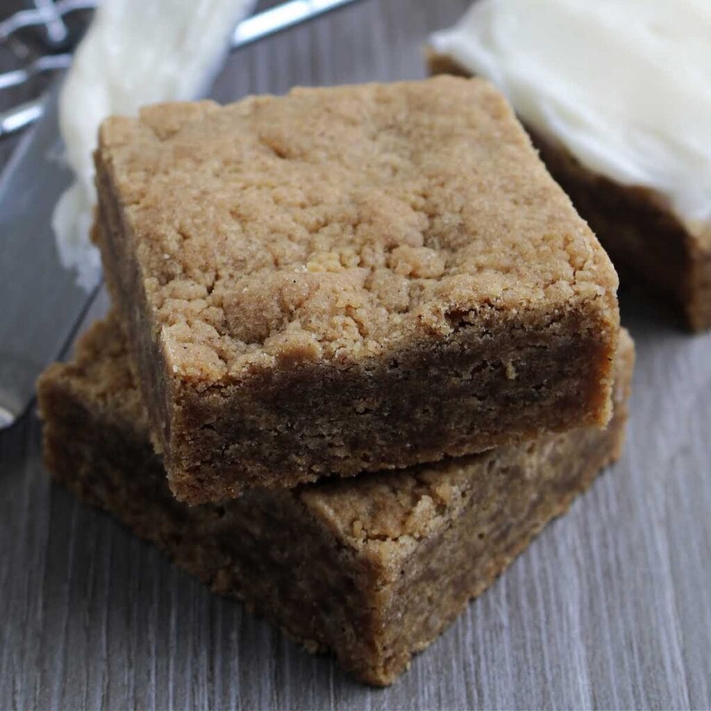 Closeup view of a stack of unfrosted gingerbread blondies on a wooden counter.