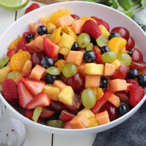 Closeup of white bowl filled with rainbow fruit salad.