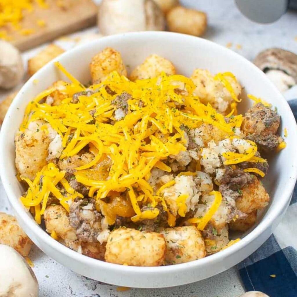 Closeup view of air fryer tater tot casserole topped with shredded cheese.