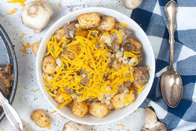 Top view of cheesy hamburger potato casserole with a spoon and napkin.