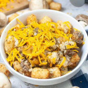 Closeup view of air fryer tater tot casserole topped with shredded cheese.