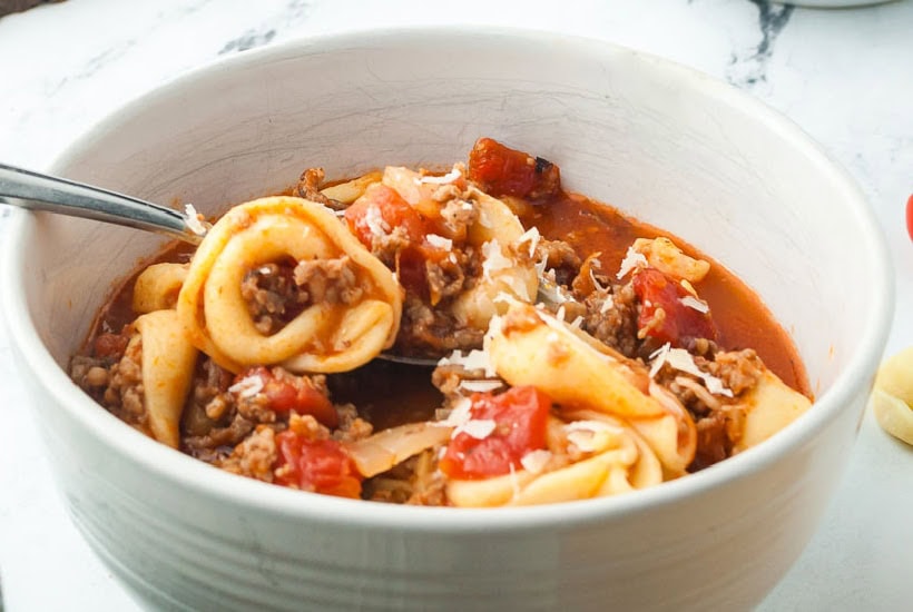White bowl filled with rustic tortellini soup.