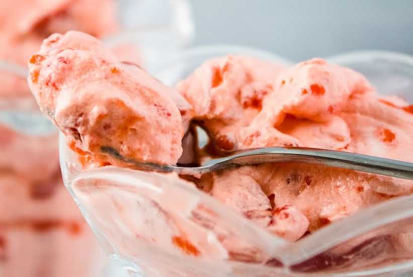 Closeup view of a spoonful of strawberries whipped cream salad.