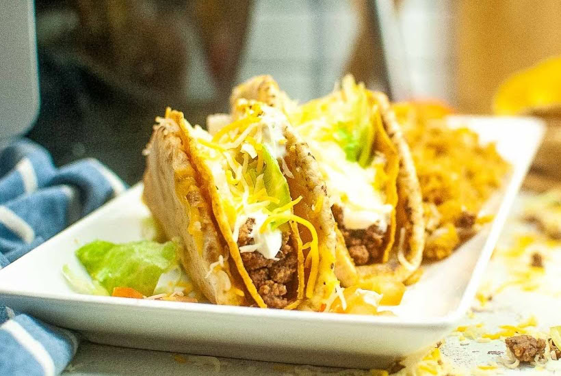 Two Taco Bell copycat cheesy Gordita crunch wraps on a white plate.