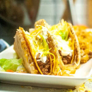 Closeup view of copycat Taco Bell cheesy gordita crunch wraps on a white plate.