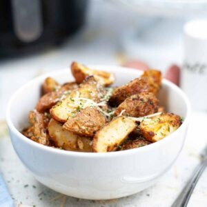 Close up view of air fried roasted potatoes in a white bowl.
