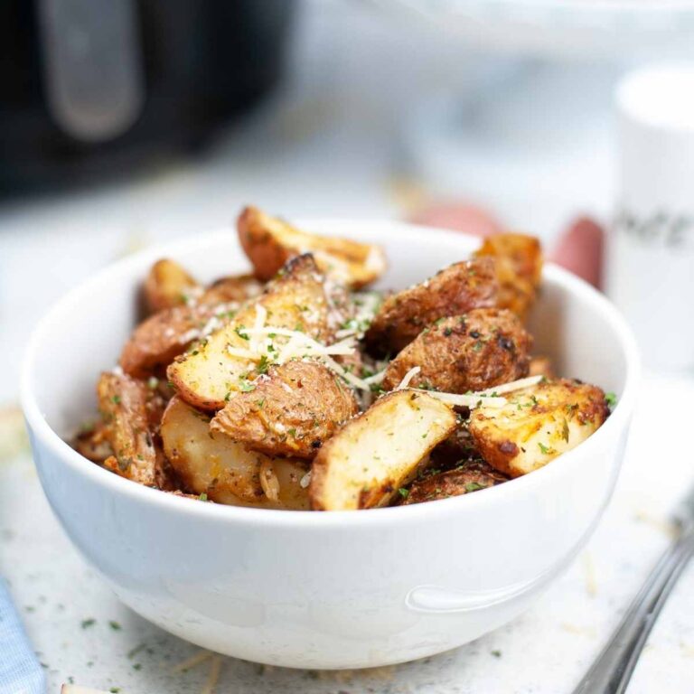Close up view of air fried roasted potatoes in a white bowl.