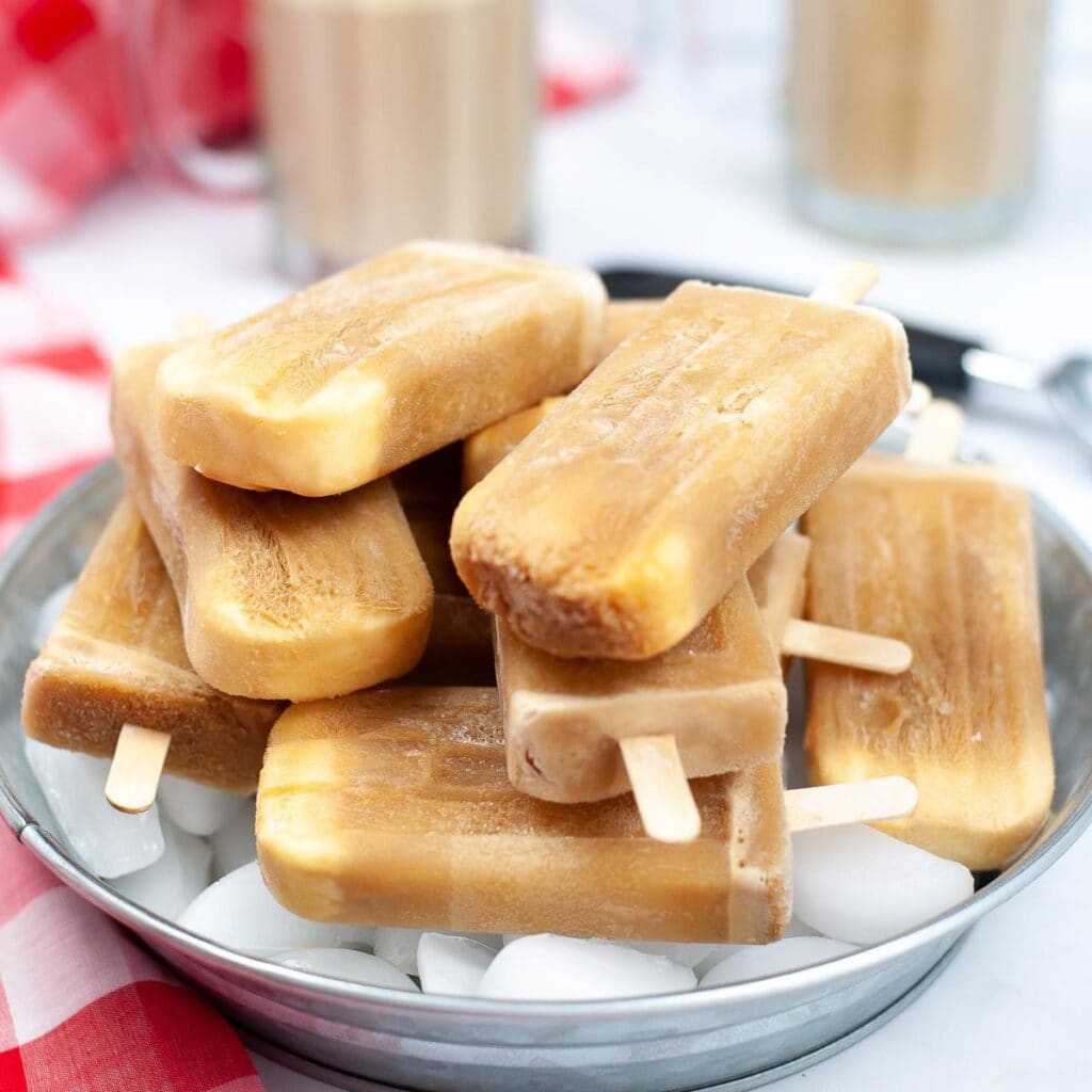 Bowl of homemade root beer float popsicles stacked on ice.