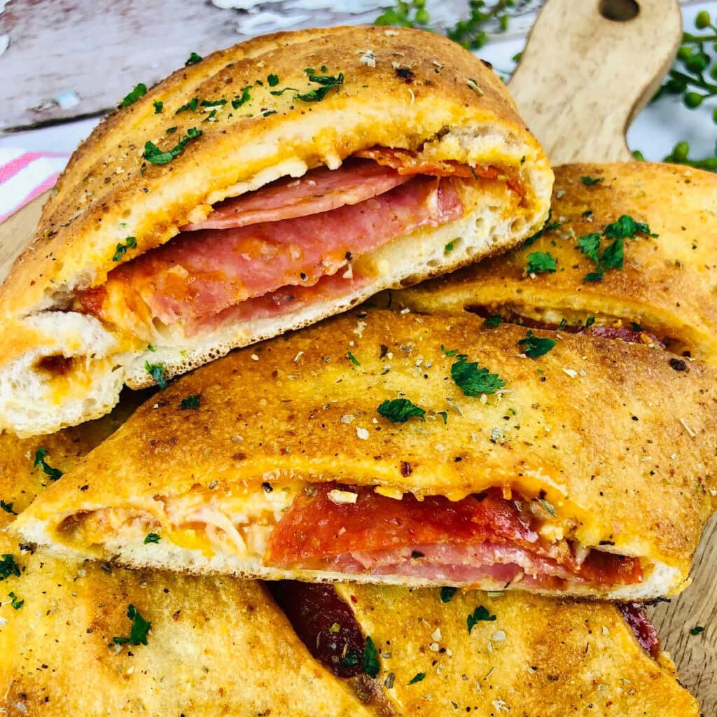 Closeup view of Italian Stromboli slices with pepperoni and salami on a wood cutting board.
