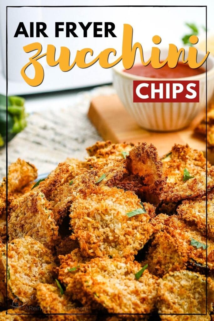 Closeup view of breaded air fryer zucchini chips with bowls of dipping sauce in the background with text overlay.