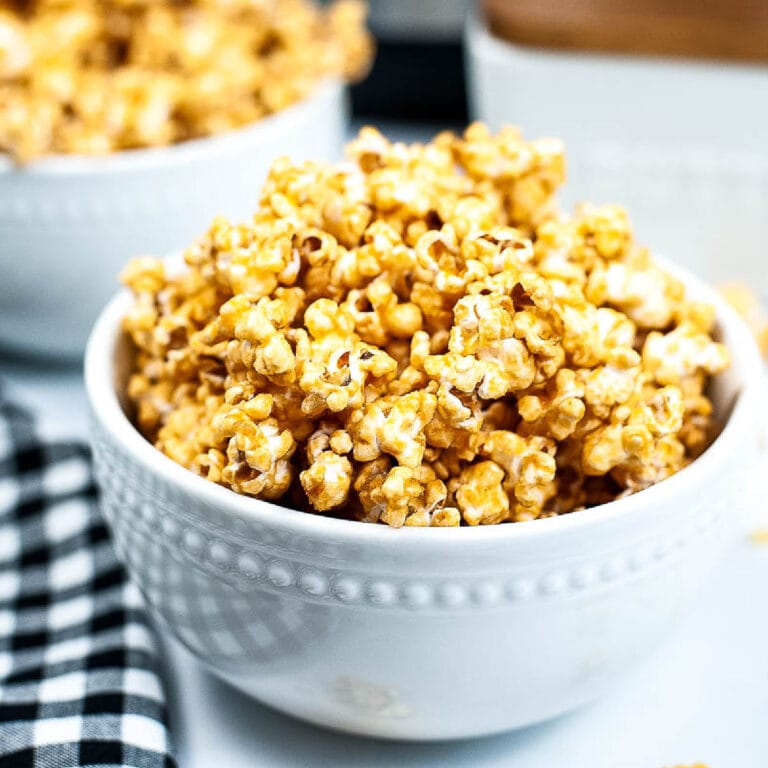 White bowl filled with homemade caramel popcorn made without corn syrup with another bowl in the background.