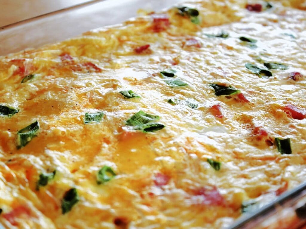 Golden baked easy breakfast casserole with ham, eggs, cheese, and hash browns in a glass baking dish.