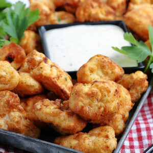 Closeup view of air fryer popcorn chicken pieces with a bowl of ranch dipping sauces.