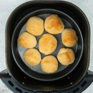 Top view of homemade air fried dinner rolls in a pan in the air fryer.
