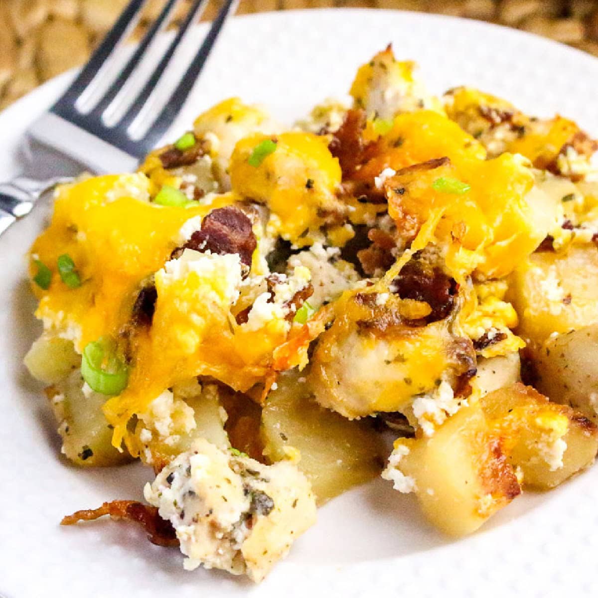 A serving of chicken bacon ranch potato bake on a white plate with a fork.