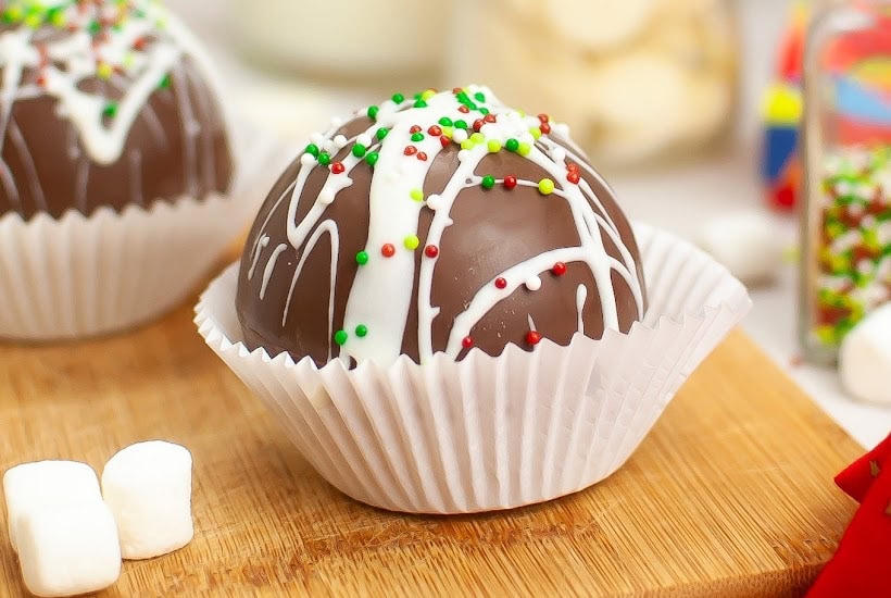 Closeup view of hot chocolate bombs in paper cups and decorated for Christmas.