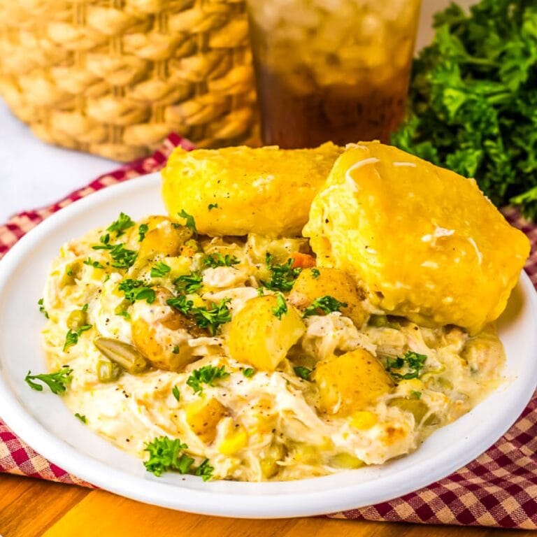 A serving of crockpot chicken pot pie with biscuits on a white plate.