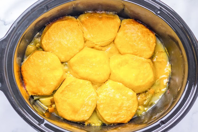 Overhead view of chicken pot pie topped with biscuits in the crockpot.