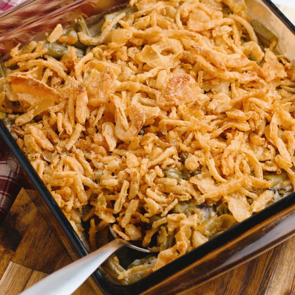 A baking dish filled with French's green bean casserole with a serving spoon.