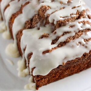Homemade cinnamon bread with icing on a white plate.