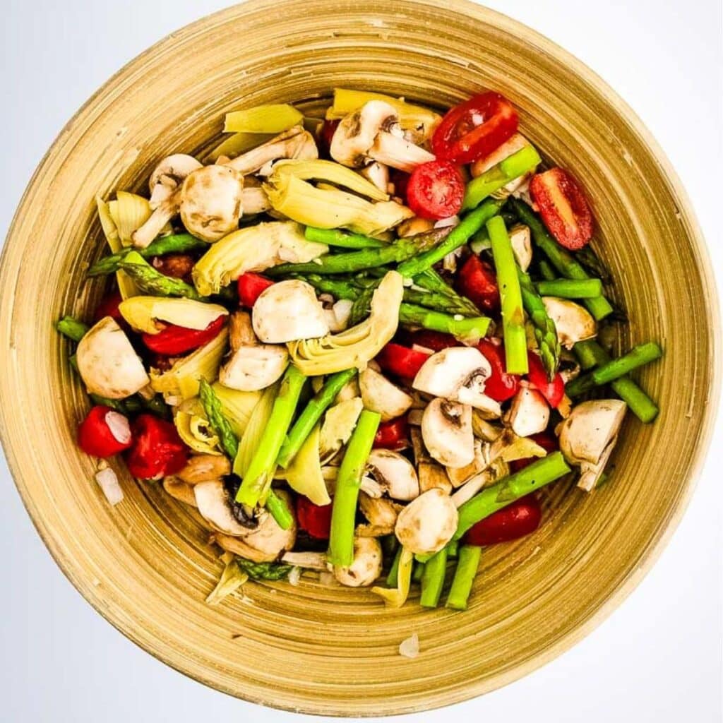 A serving bowl filled with easy vegetable salad with dressing.