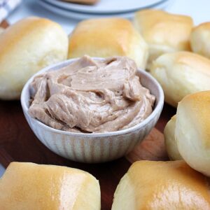 A bowl of copycat Texas Roadhouse cinnamon butter with honey in a ramekin surrounded by rolls.