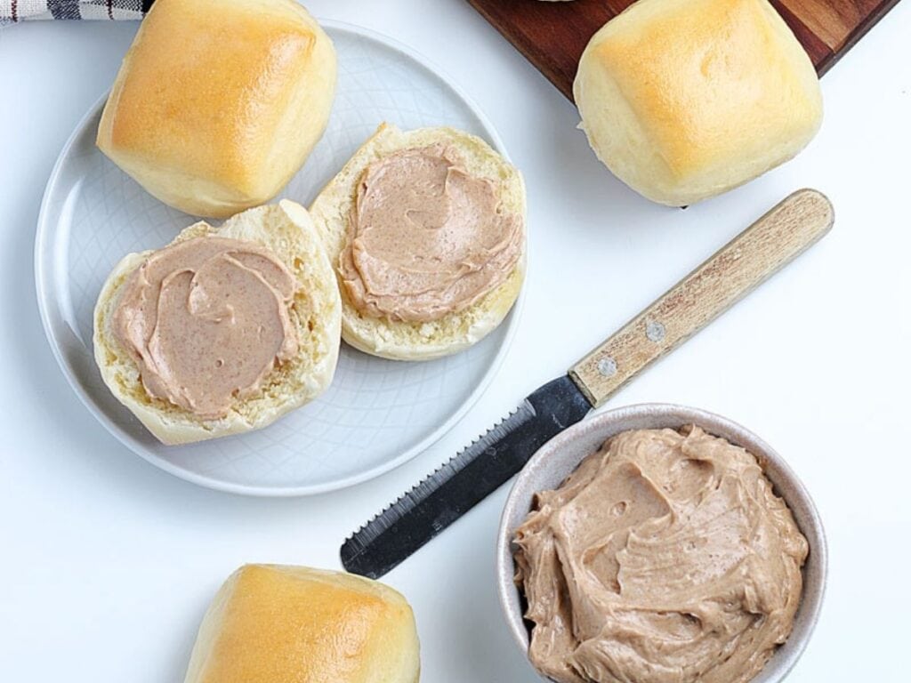 A bowl of homemade Texas Roadhouse butter in bowl with some spread on a roll.