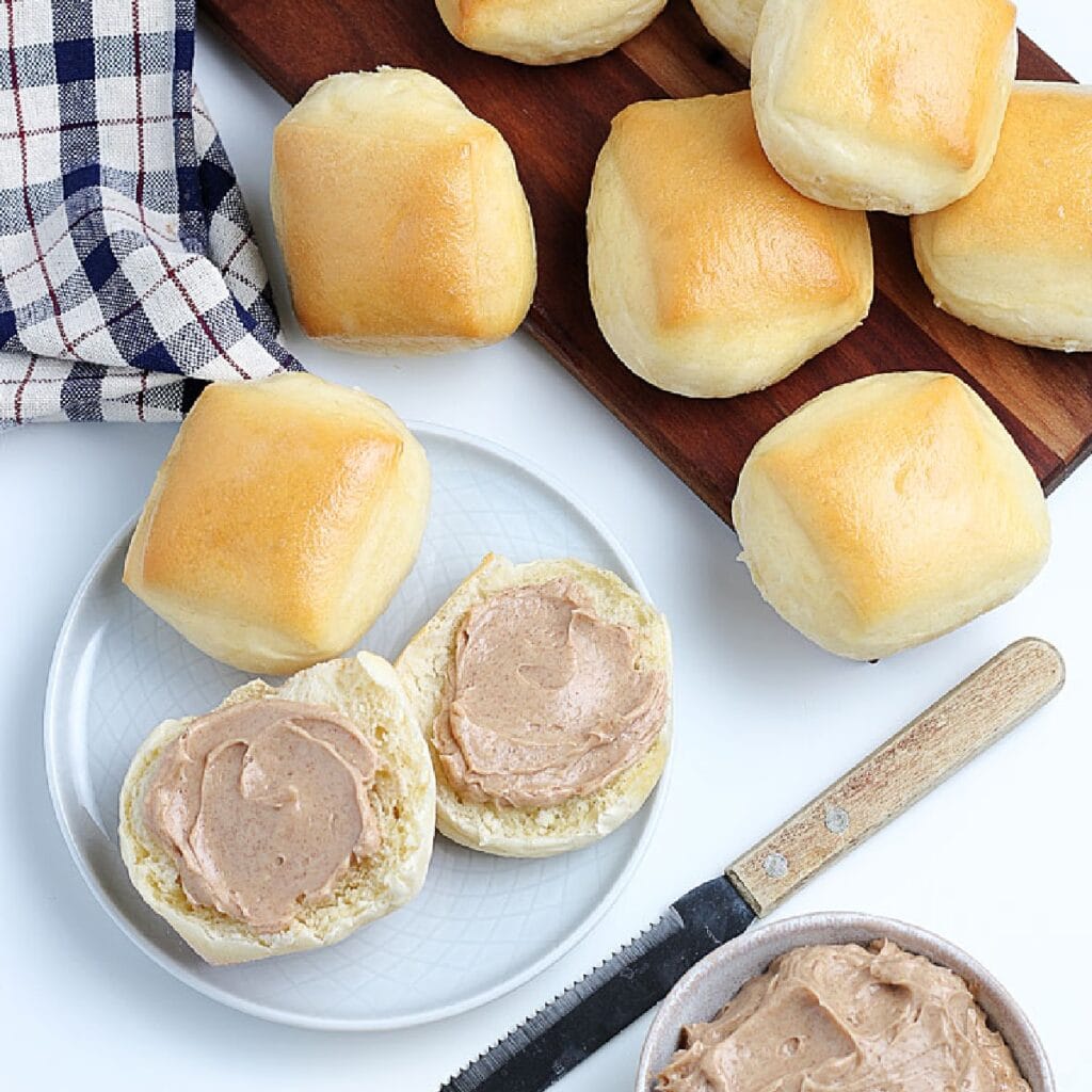 Copycat Texas Roadhouse Rolls on a tray with one open topped with cinnamon honey butter.