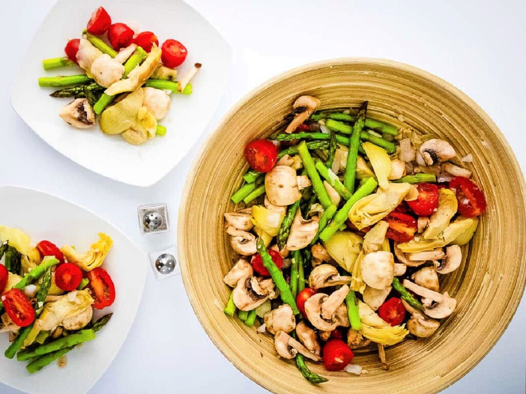 A serving bowl of spring vegetable salad with two individual servings on plates with text overlay.