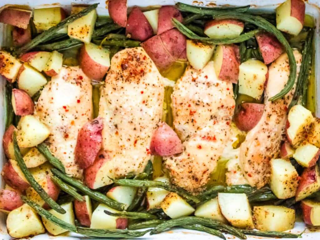 Baked sheet pan Italian chicken potatoes and green beans in a casserole dish.